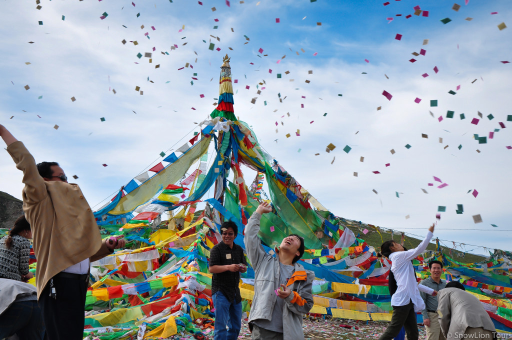 тибетец кидает бумажные Лунгта на перевале Ларци, Амдо
